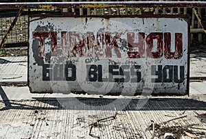 Weathered sign in the street proclaims Ã¢â¬ÅThank You, God Bless YouÃ¢â¬Â in Batangas, the Philippines.